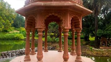 A pavilion with intricate carvings and a pond in the background.