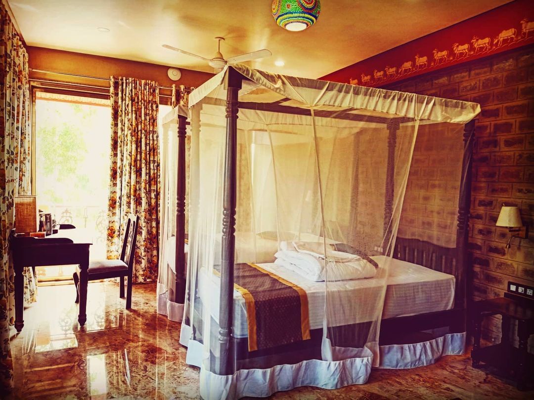 A room with a four-poster bed, a ceiling fan, and a brick wall.