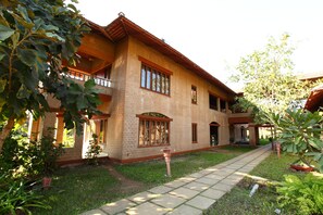 A two-story building with a brick facade, large windows, and a covered porch area. - Govardhan Eco Village (Vada)