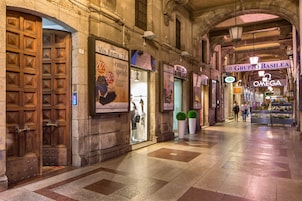 Un corridoio con negozi, tra cui uno con la scritta Via Roma e un altro con il marchio Omega.