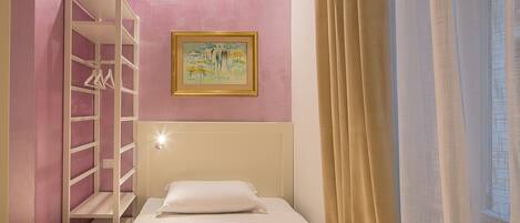 A bedroom with a bunk bed, a painting on the wall, and a window with curtains.