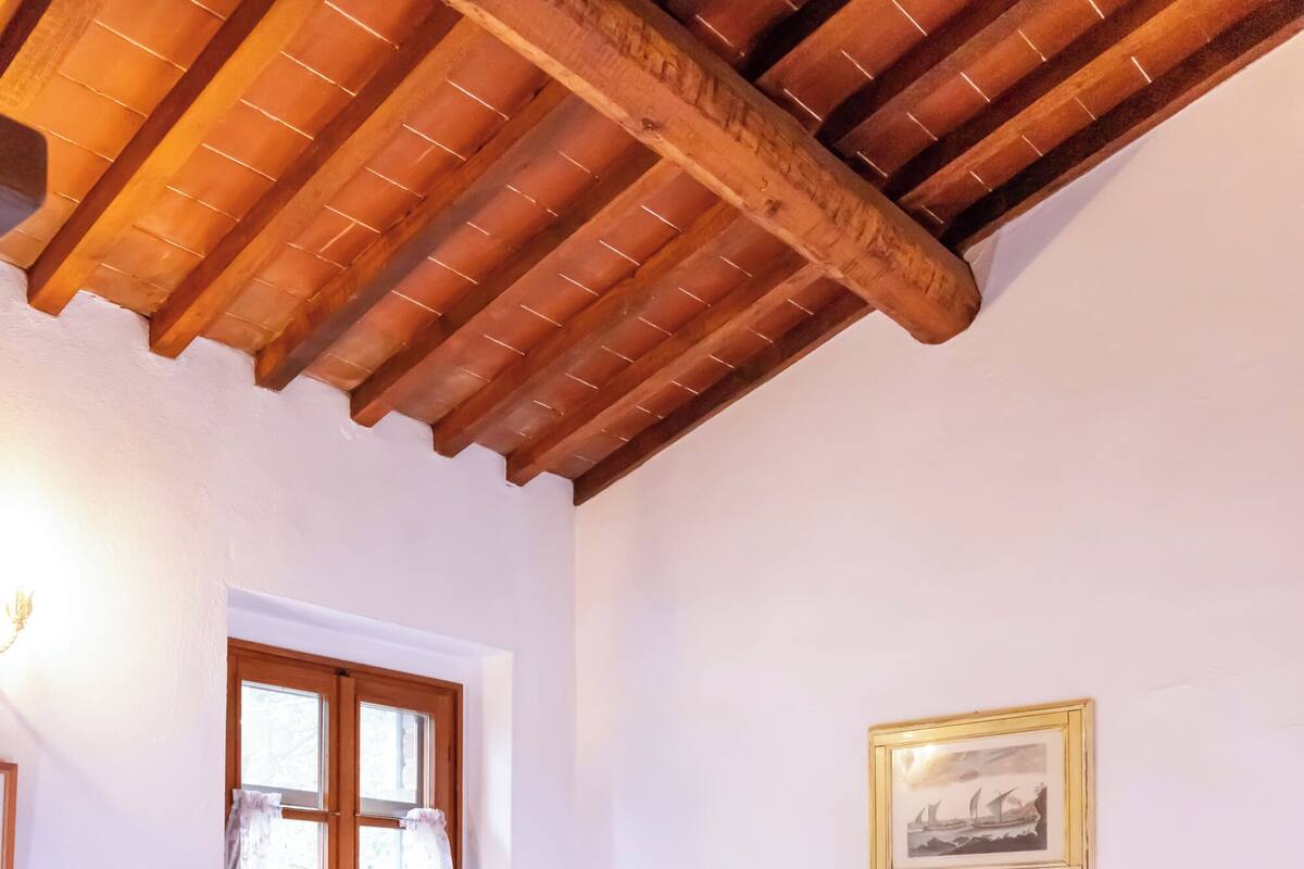 Une chambre à coucher avec un lit, une fenêtre avec des rideaux, un tableau accroché au mur et un sol carrelé.