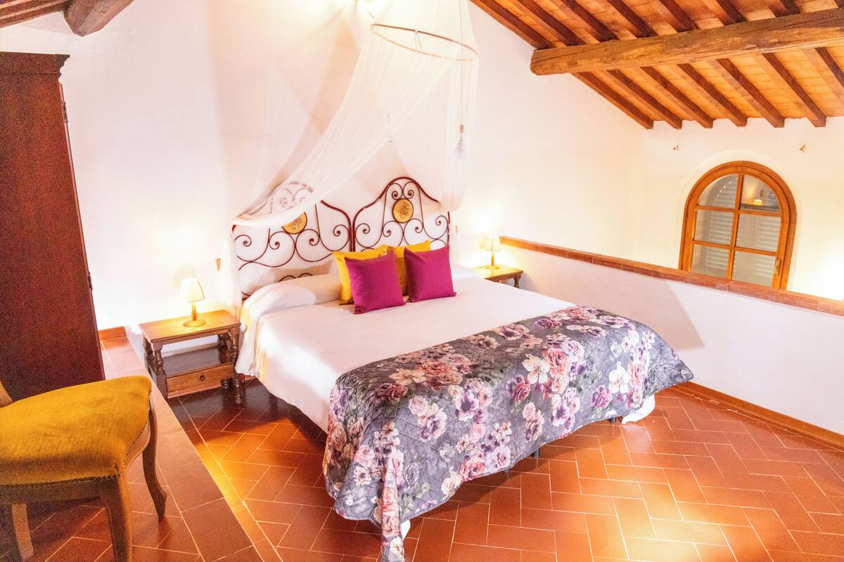 Une chambre à coucher comprenant un lit, une table de chevet, une chaise et une fenêtre avec un cadre en bois.