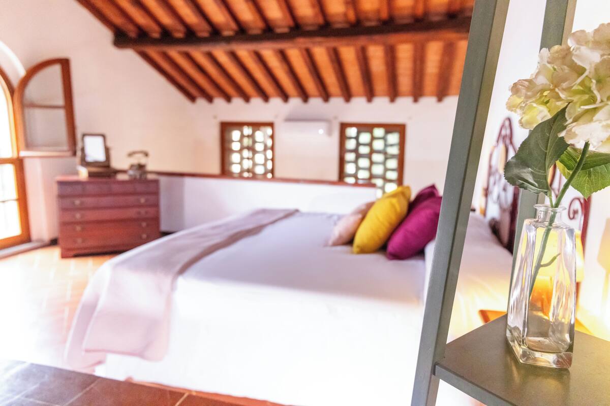 Une chambre à coucher avec un lit, une commode et un vase rempli de fleurs.