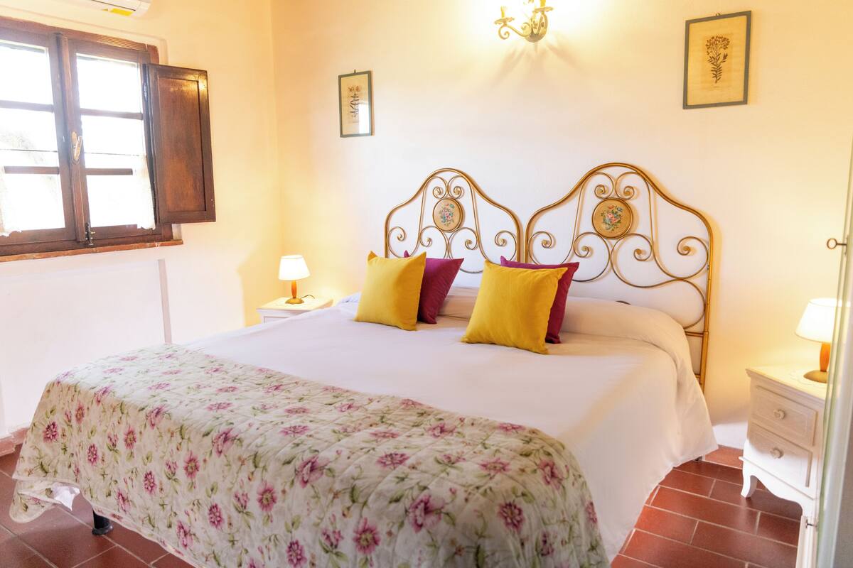 Une chambre à coucher comprenant un lit, deux tables de chevet, une fenêtre et des éléments de décoration murale.