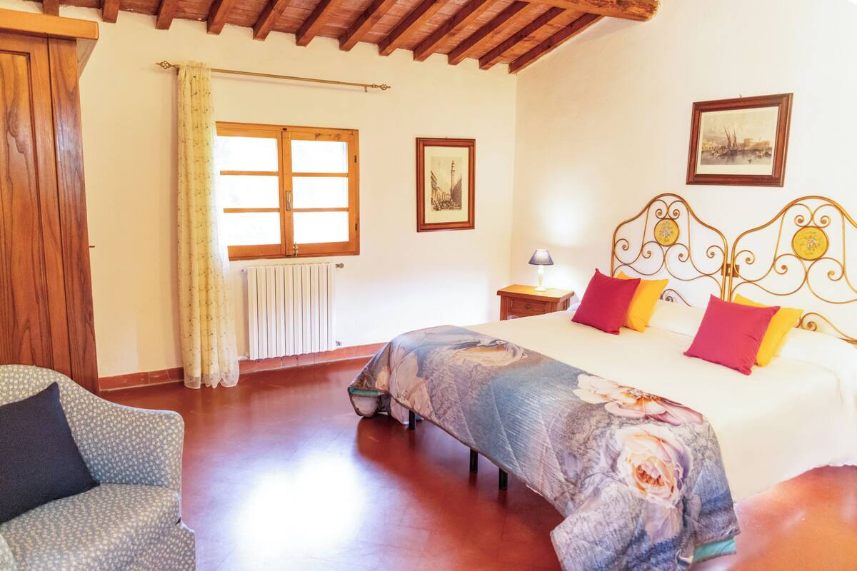 Une chambre à coucher avec un lit, une chaise, une fenêtre, un radiateur et un tableau au mur.
