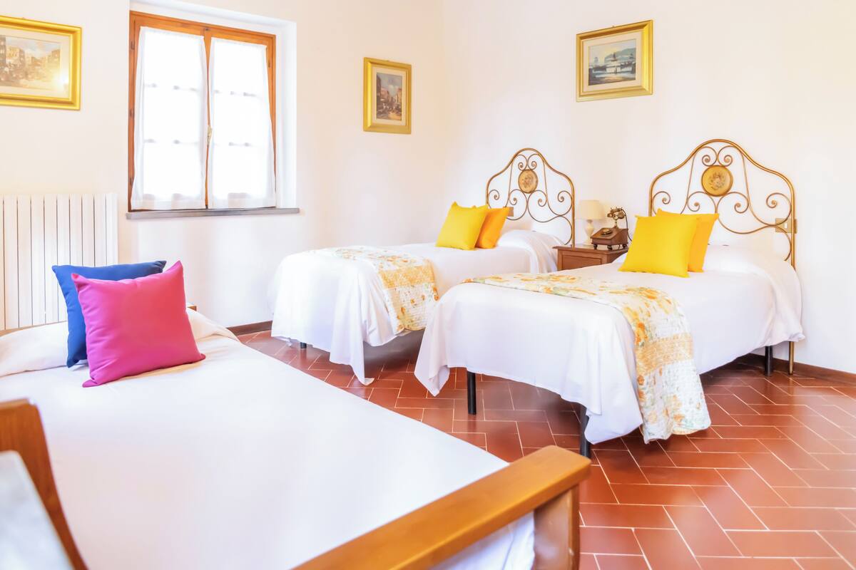 Une chambre d’hôtel avec deux lits, une fenêtre et un radiateur.