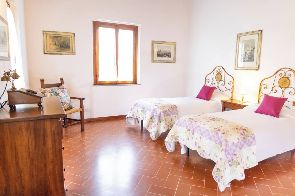 Une chambre avec deux lits, un bureau, une chaise et une fenêtre.