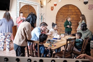A group of people engaged in a board game in a room with wooden arches and a checkered flag on the wall. - Borgo Il Poggio Agriturismo (Montaione)
