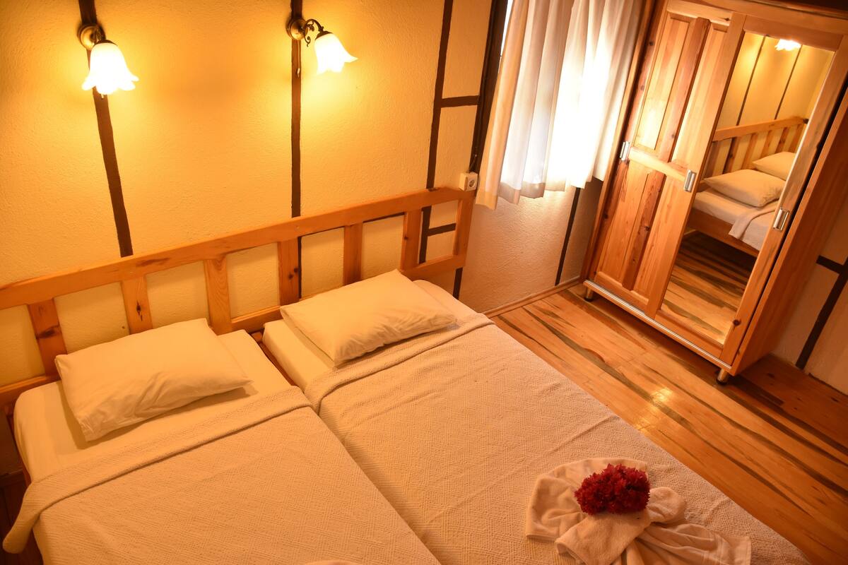 Une chambre avec deux lits, des têtes de lit en bois et une armoire en bois.