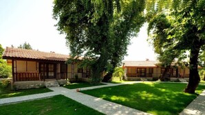A traditional building with a tiled roof, surrounded by well-maintained grass and trees.