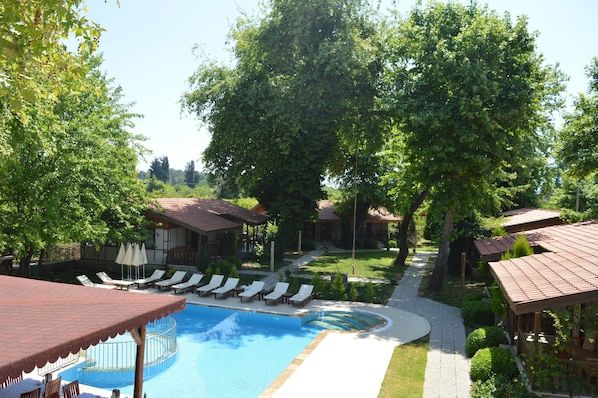 Zona de piscina con sillones de descanso y una zona de estar cubierta.