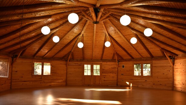 A spacious wooden interior with a high ceiling and multiple windows.