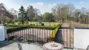 A fenced outdoor area with a paved patio and a round table. - Bongate House (Appleby-in-Westmorland)