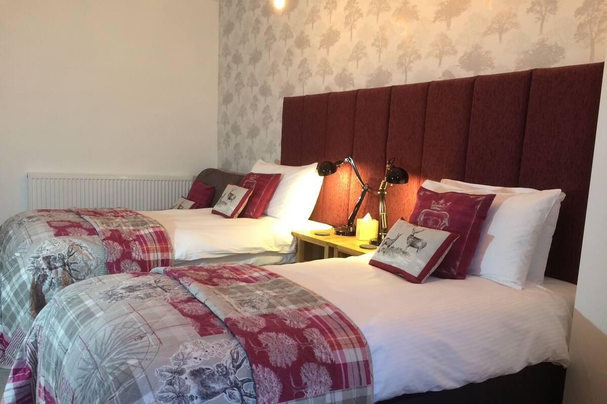 A double bed with a red headboard, two bedside tables with lamps, and a floral-patterned bedspread.