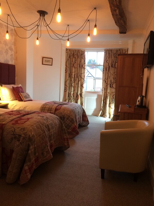 A bedroom with a large bed, a chair, a wooden wardrobe, and a window with curtains. - Bongate House (Appleby-in-Westmorland)