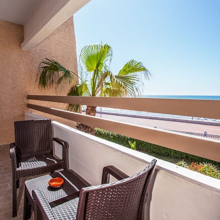 A balcony with wicker furniture and a view of the sea.