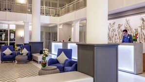 A spacious lobby with a checkered floor, blue seating, and a reception desk. - Dunes d'Or Ocean Club (Agadir)