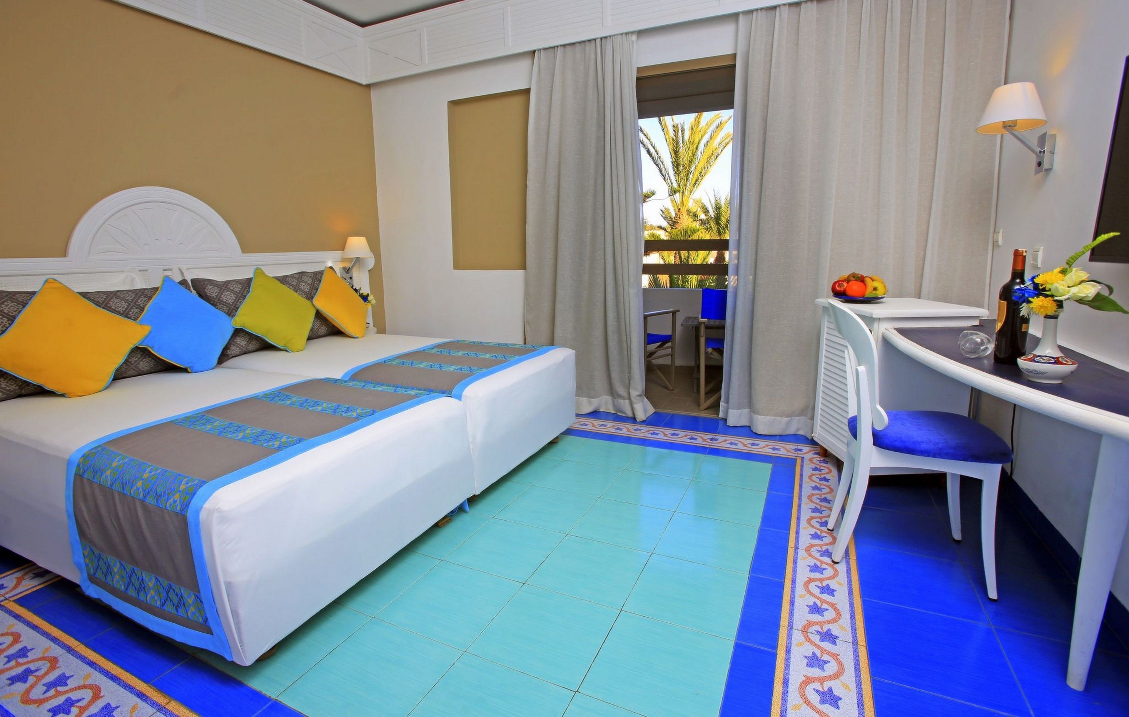 A hotel room with a bed, a desk, and a view of the outdoors.