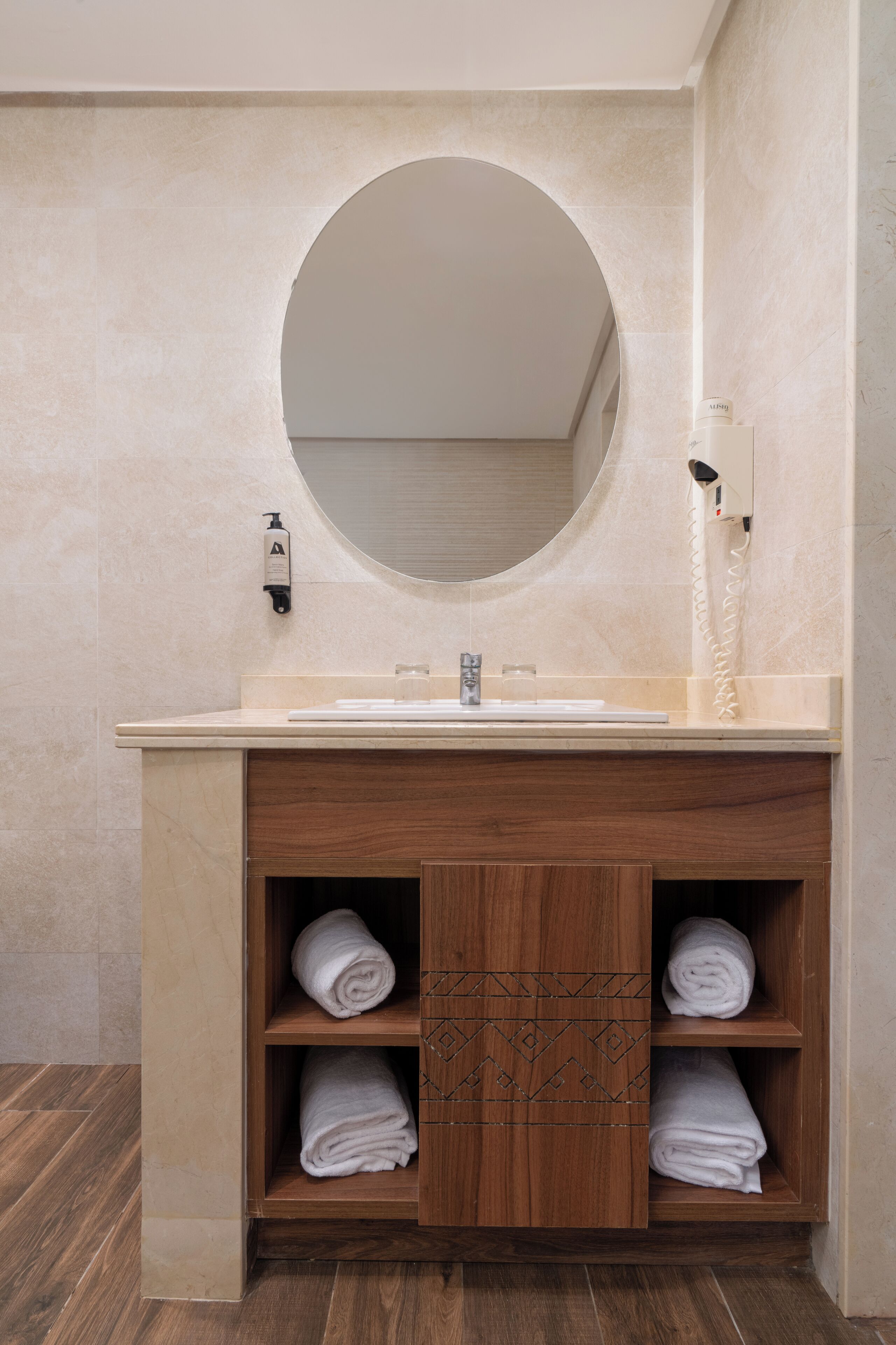 A bathroom with a round mirror, a sink, and a towel rack.