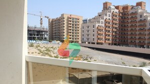 A view from a balcony overlooking a construction site with buildings under development and a parking area with cars.