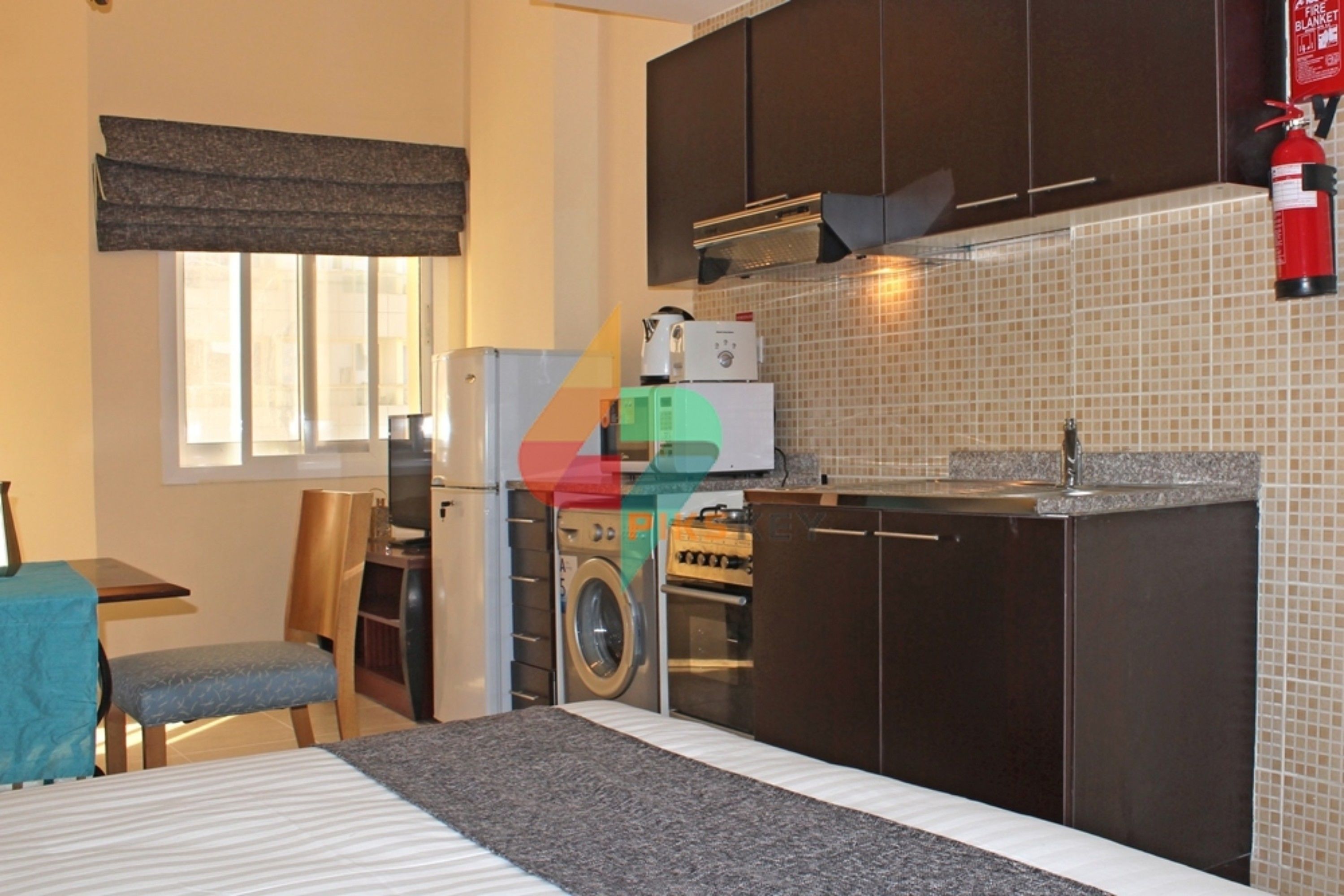 A compact kitchen with a washing machine, a microwave, and a stove.