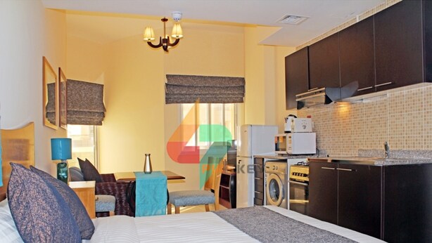 A bedroom with a bed, a chair, a desk, and a washing machine.