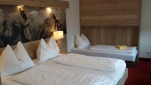 Habitación de hotel con dos camas, cabecero de madera, un cuadro grande y una lámpara de noche.