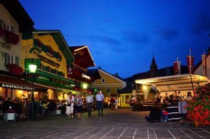 A square with outdoor seating and a covered area, surrounded by buildings with traditional architecture and signage. - Hotel Lammertalerhof (Abtenau)