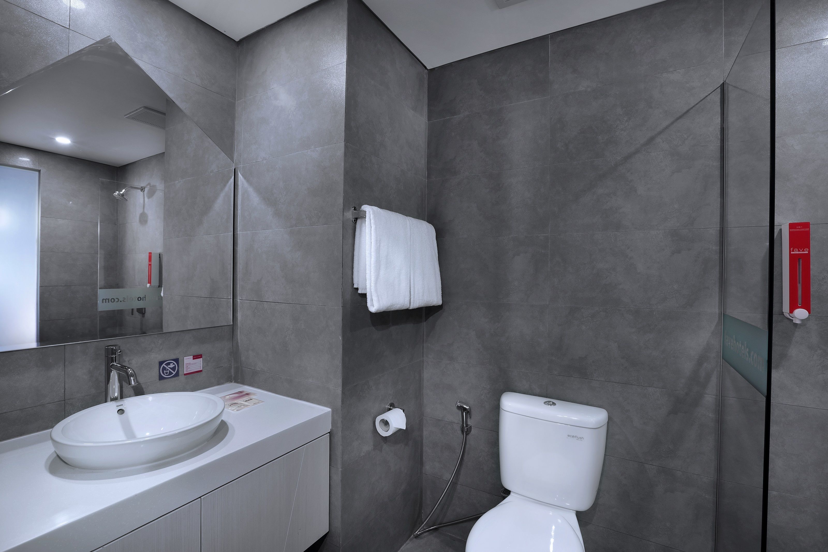A modern bathroom with a white sink, a toilet, and a glass-enclosed shower.
