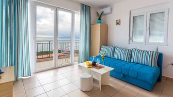 Apartment, 1 Bedroom, Sea View | Living room | Flat-screen TV, books