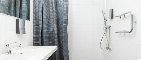 Ein modernes Badezimmer mit einem weißen Waschbecken, einer Dusche mit Duschbrausehandstück und einem Handtuchhalter.