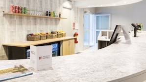 A hotel reception area with a marble counter, a reception desk, and a wall-mounted shelf with various items. - Karlskoga Hotell (Karlskoga)