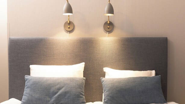 A neatly made bed with two pillows, a folded towel, and a magazine on the bed. - Karlskoga Hotell (Karlskoga)