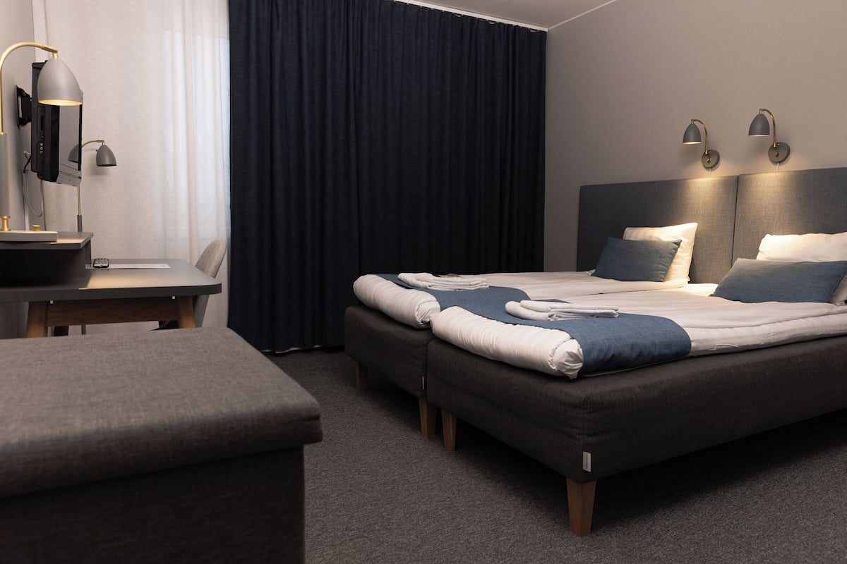 A modern hotel room with a large bed, bedside tables, a desk, and a chair.