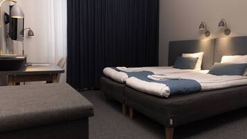 Une chambre d’hôtel moderne, dotée d’un grand lit, de tables de chevet, d’un bureau et d’une chaise.