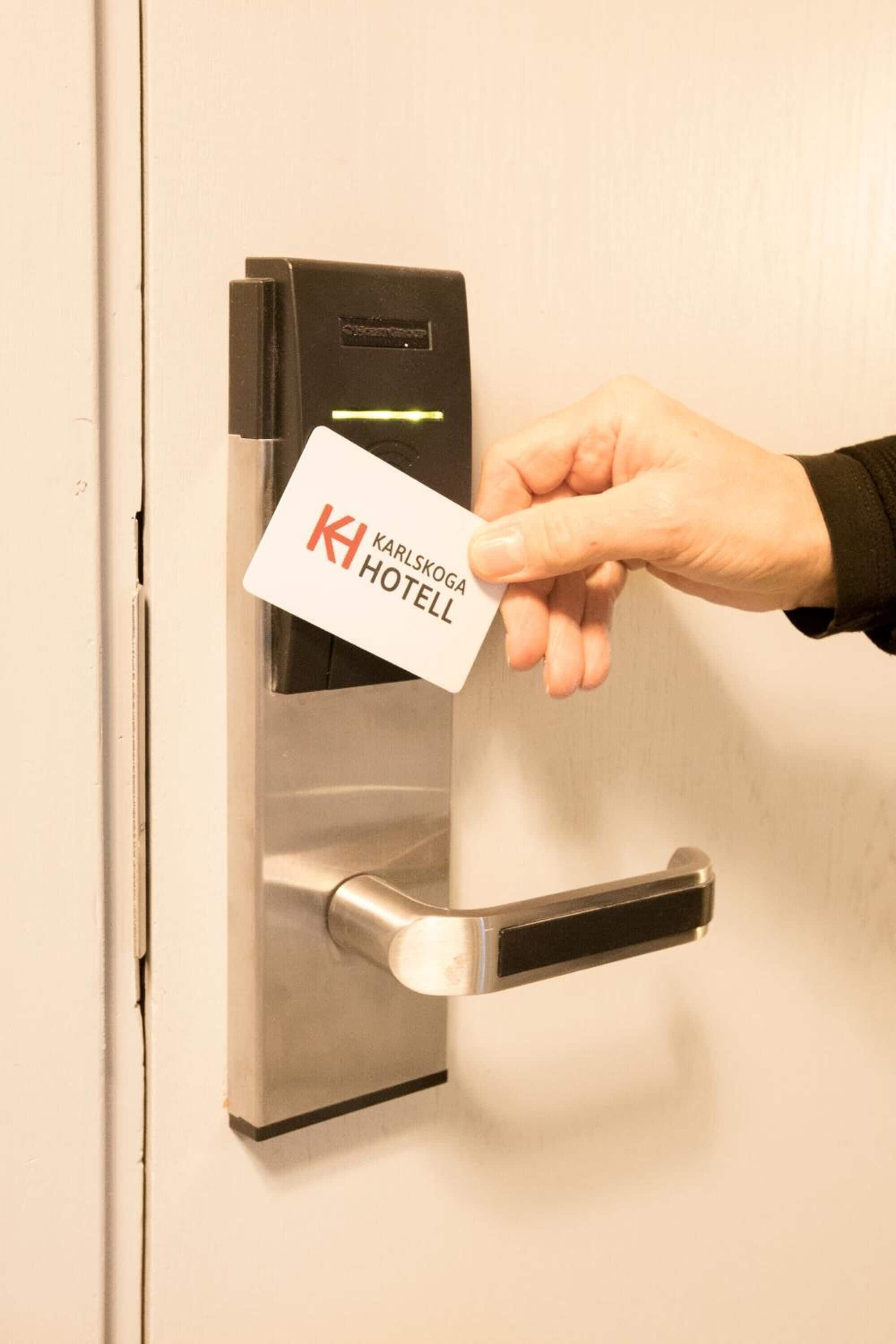A hand inserting a card into a card reader on a door.