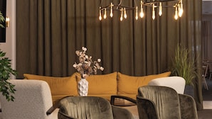 A modern interior with a sectional sofa, two armchairs, a small round table, and a hanging light fixture. - Karlskoga Hotell (Karlskoga)