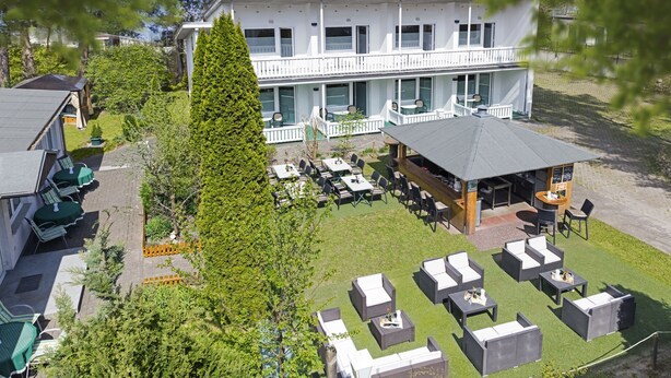 A two-story building with a balcony, outdoor seating area, and a small bar. - Hotel Waldidyll (Ostseebad Baabe)