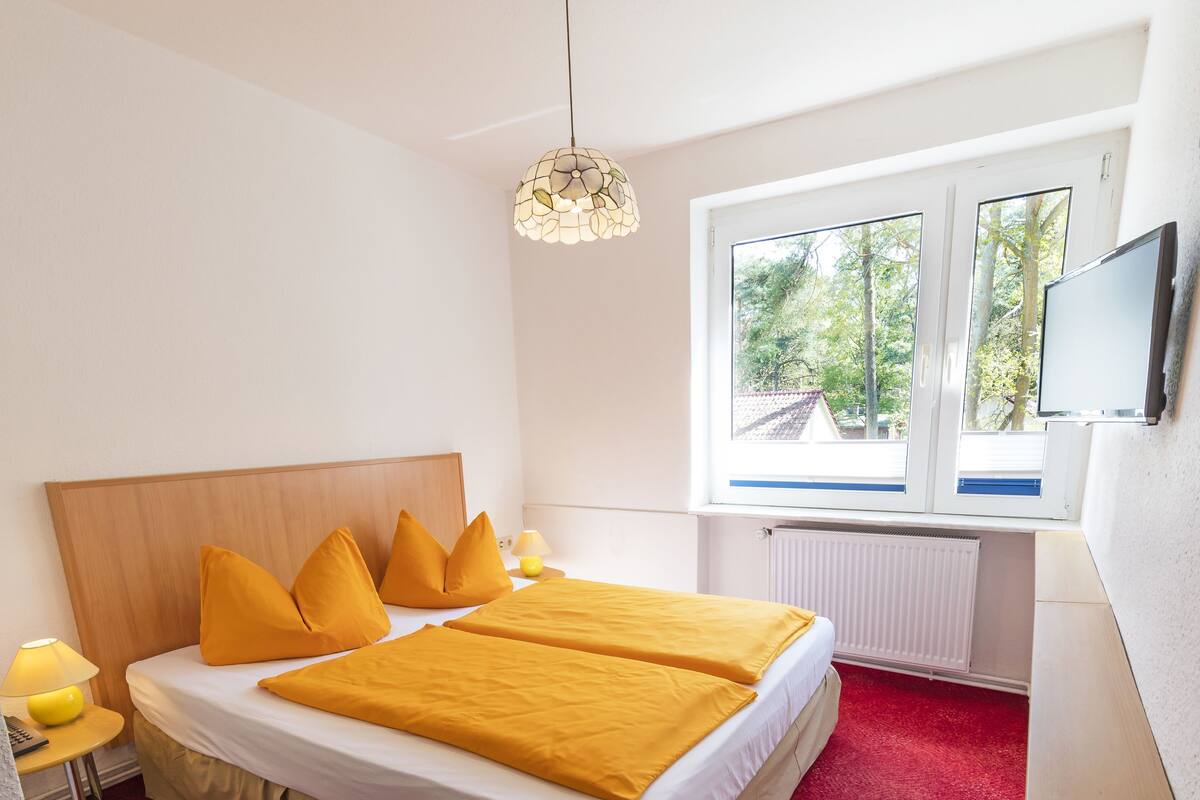 Una habitación de hotel con cama, escritorio, silla, ventana y televisor.