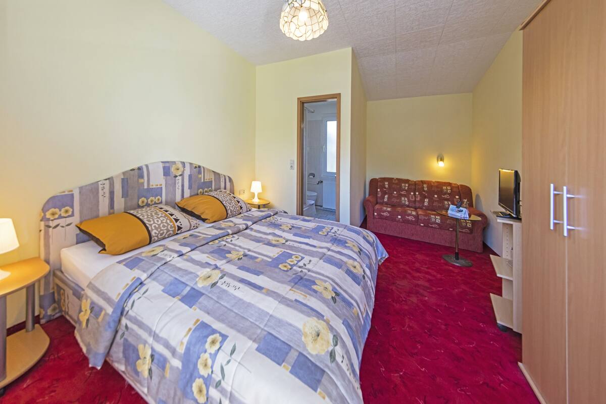 Un dormitorio con cama, mesitas de noche, televisor y armario.