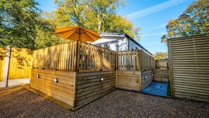 A wooden fenced outdoor area with a covered seating area and a small pool. - The Travellers Rest (Halesworth)