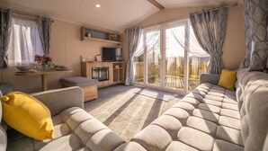 A cozy living room with a sofa, a TV, and a dining table. - The Travellers Rest (Halesworth)