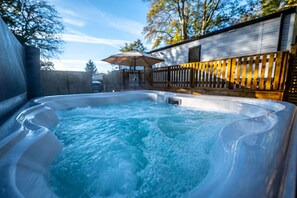 A hot tub in a backyard with a wooden deck and a fence. - The Travellers Rest (Halesworth)