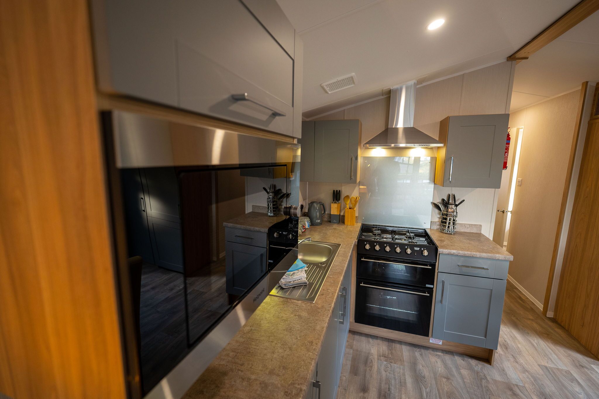 Une cuisine moderne dotée d’un îlot central, d’appareils électroménagers en acier inoxydable et de meubles de rangement en bois.