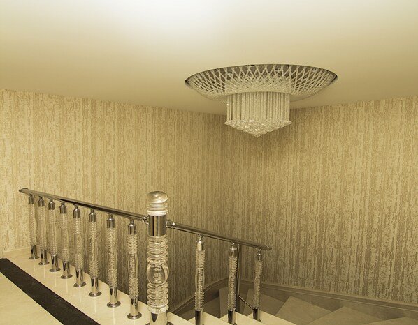 A staircase with a metal railing and a decorative chandelier.