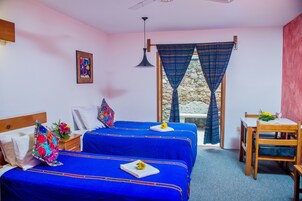 Una habitación con dos camas, una mesita y una ventana con cortinas.