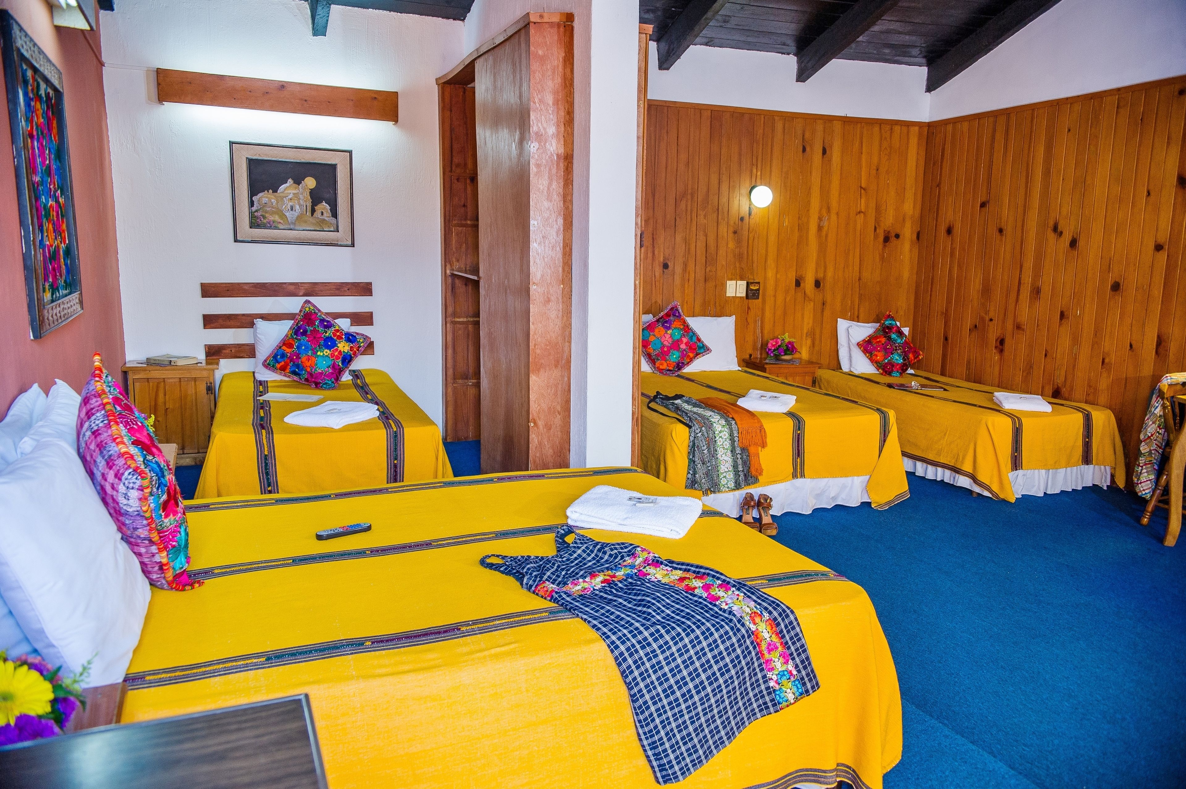 Una habitación de hotel con dos camas, paredes de madera y una alfombra azul.
