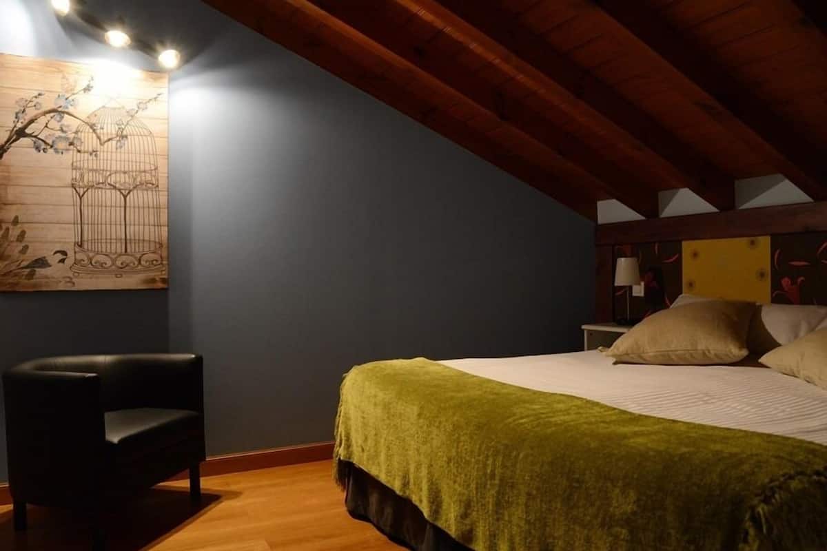 Une chambre à coucher comprenant un lit, une chaise, une table de chevet et une œuvre d’art murale.