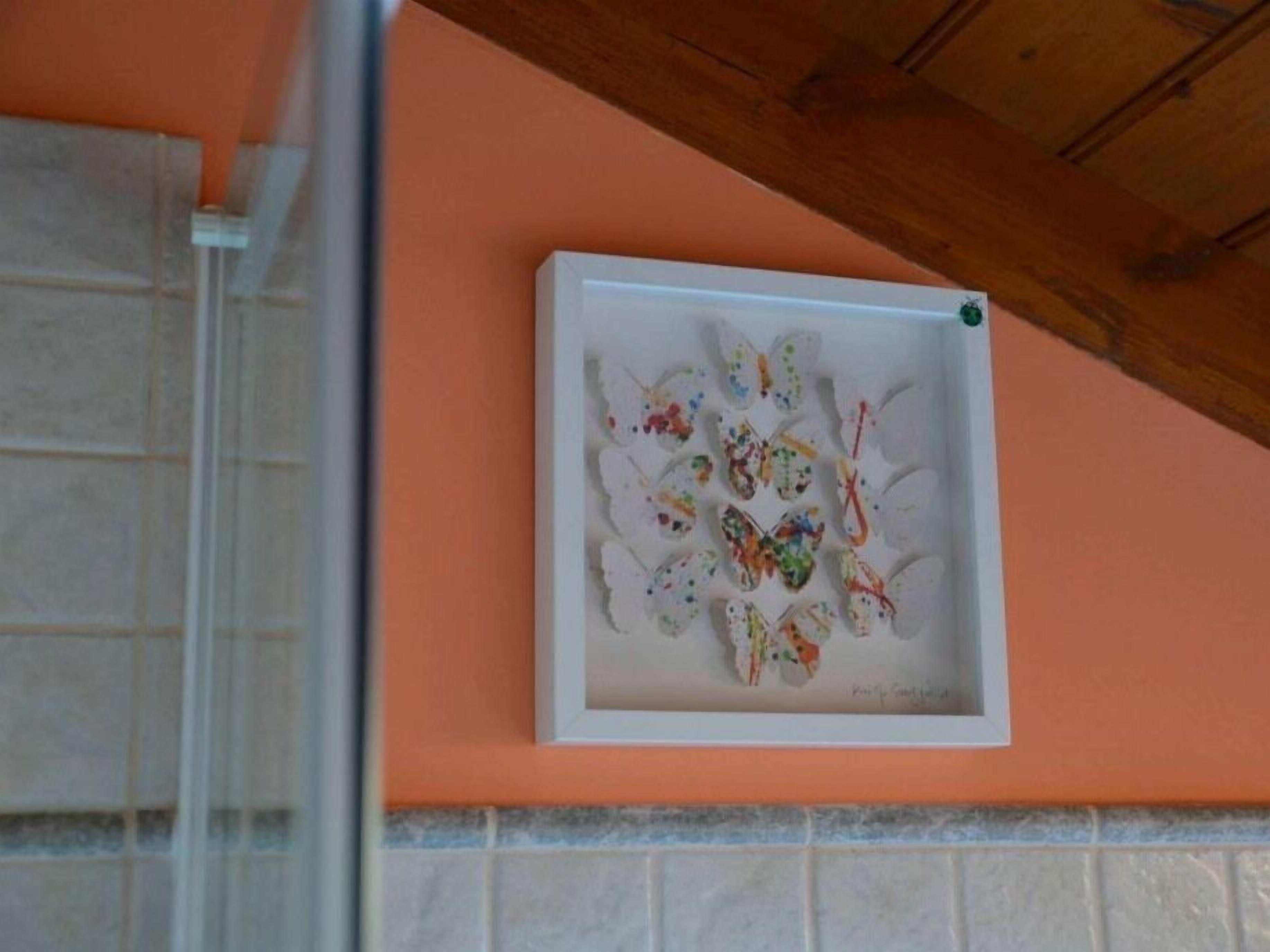 A framed artwork of butterflies on a wall.
